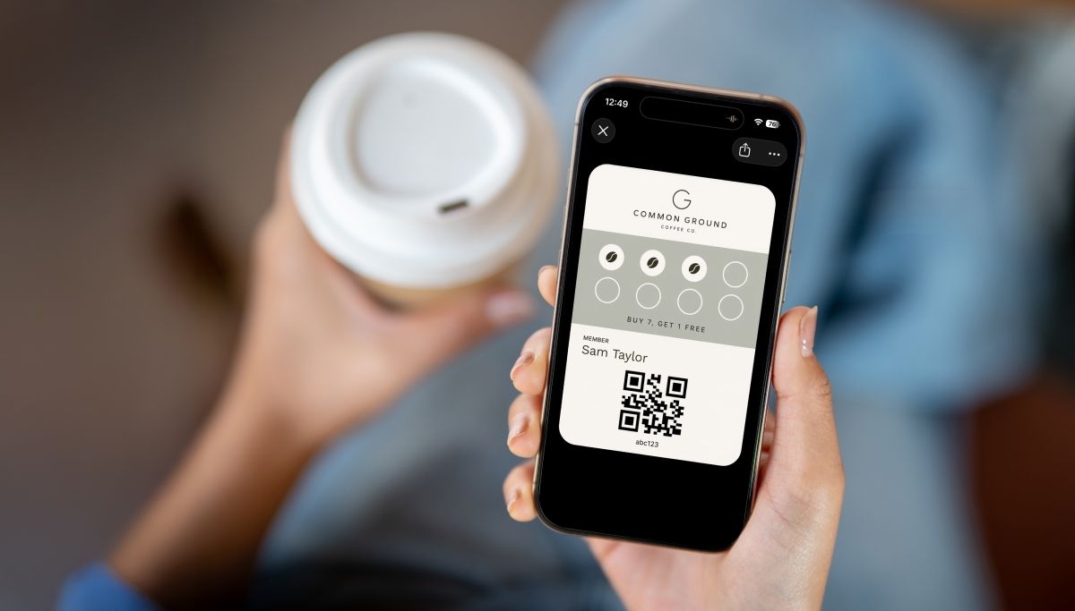 A printed Coffee Corner loyalty card on a café counter while a customer scans the QR code with their phone
